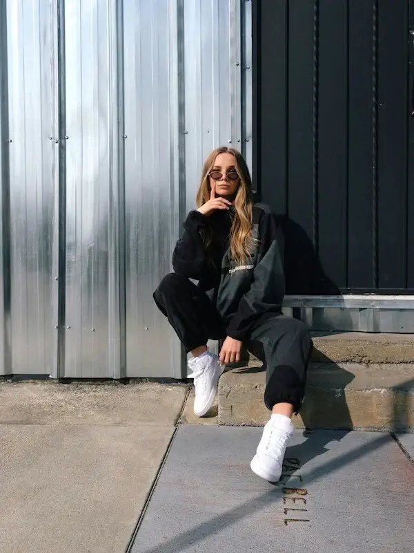 woman posing on steps in a jogger suit and white sneakers