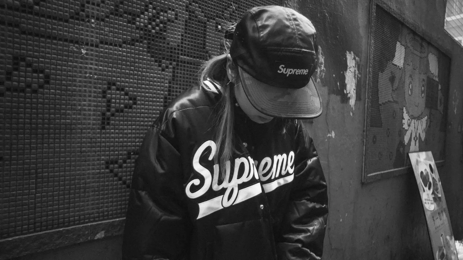 woman in subway with head down wearing Supreme clothing